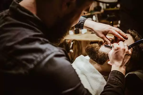 image of barber grooming the client beard