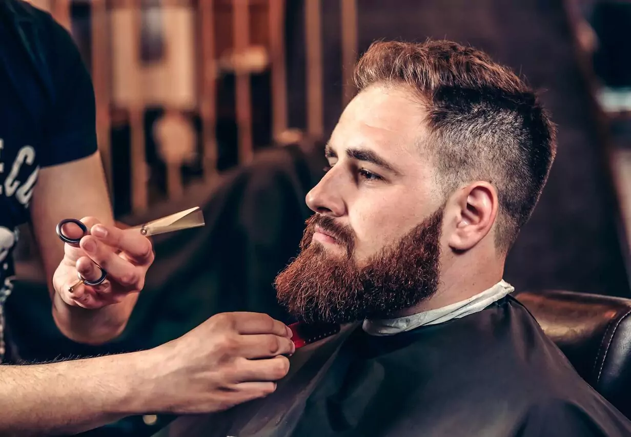 image of barber grooming the client beard